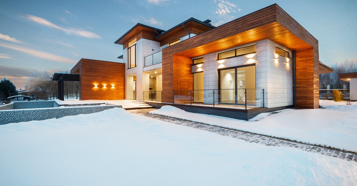 How do machines know the exact location of Zion? - Exterior architecture of private suburban cottage house with stone and wooden facade and large windows overlooking spacious snow covered yard in winter day