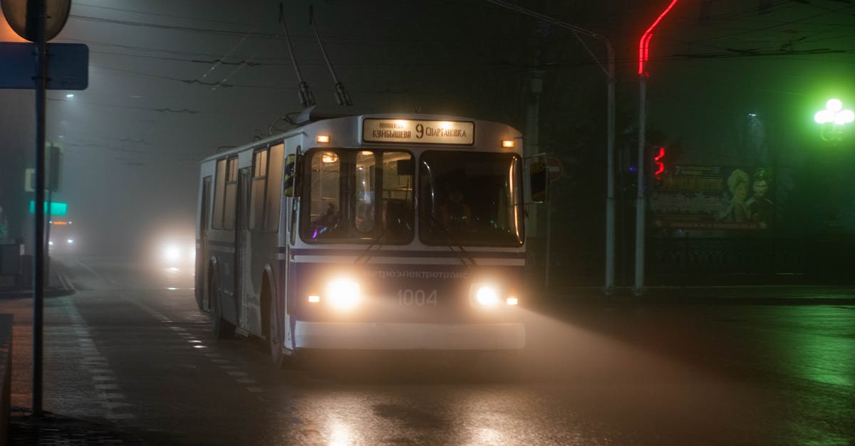 How do movies make small places fog up - Old trolleybus driving along wet asphalt road in small city at foggy night