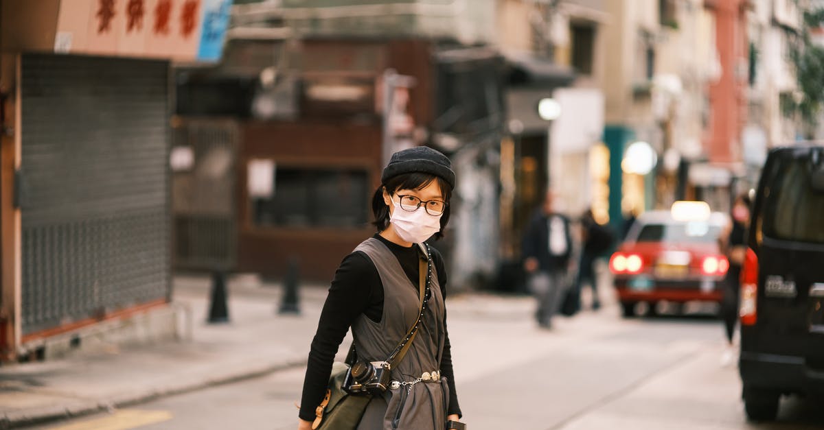 How do rashes relate to chinese cars? - Asian Woman in Specs and Face Mask Crossing Street in Chinese City