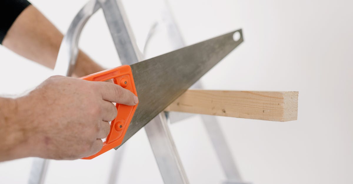 How do the SAW movies achieve dismemberment on screen? - Crop man sawing wooden plank at home