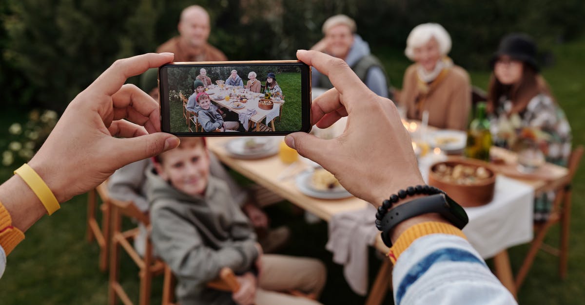 How do they shoot flaming human scenes? - Unrecognizable person taking photo of family dinner on smartphone
