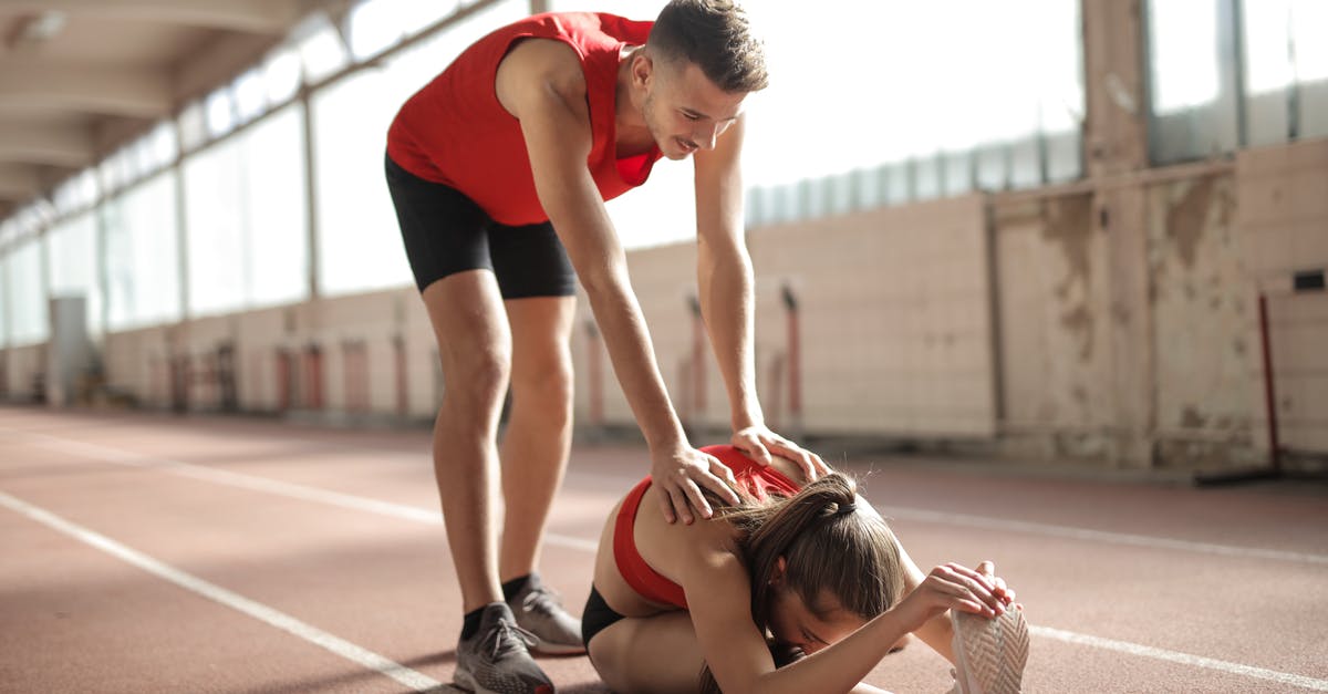 How do Trainers keep track of which Pokéball belongs to which Pokémon? - Professional male sportsman helping woman touching knees with head while female sitting on running track and doing stretching exercise