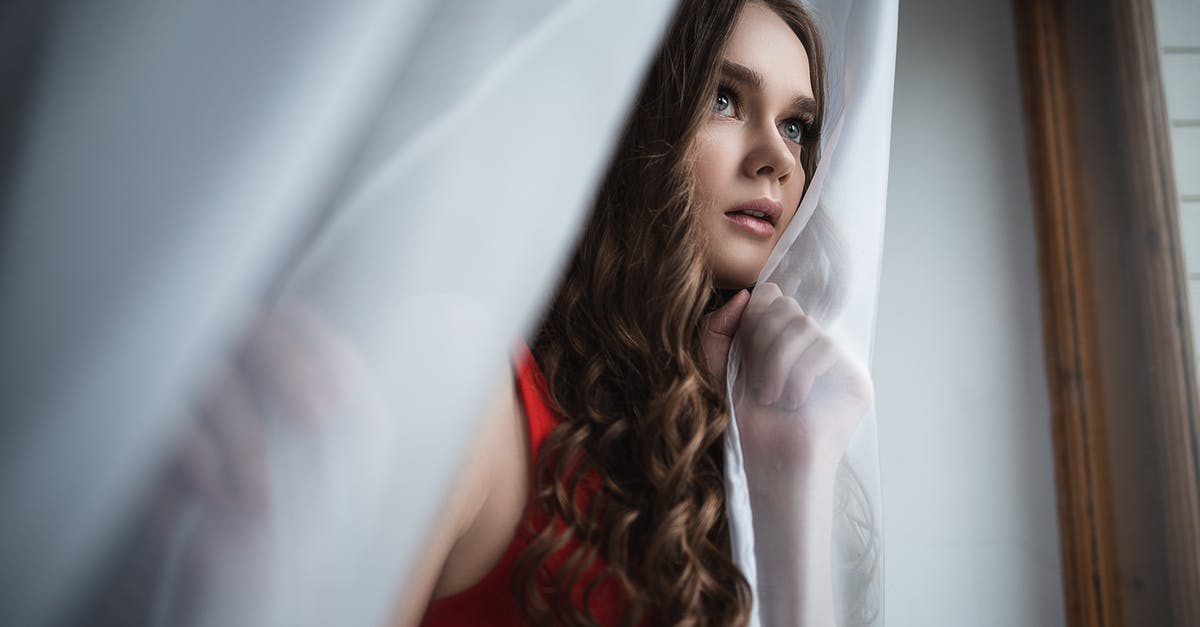 How does Adrian Toomes hide his earnings from the IRS? - Thoughtful young woman standing near curtains