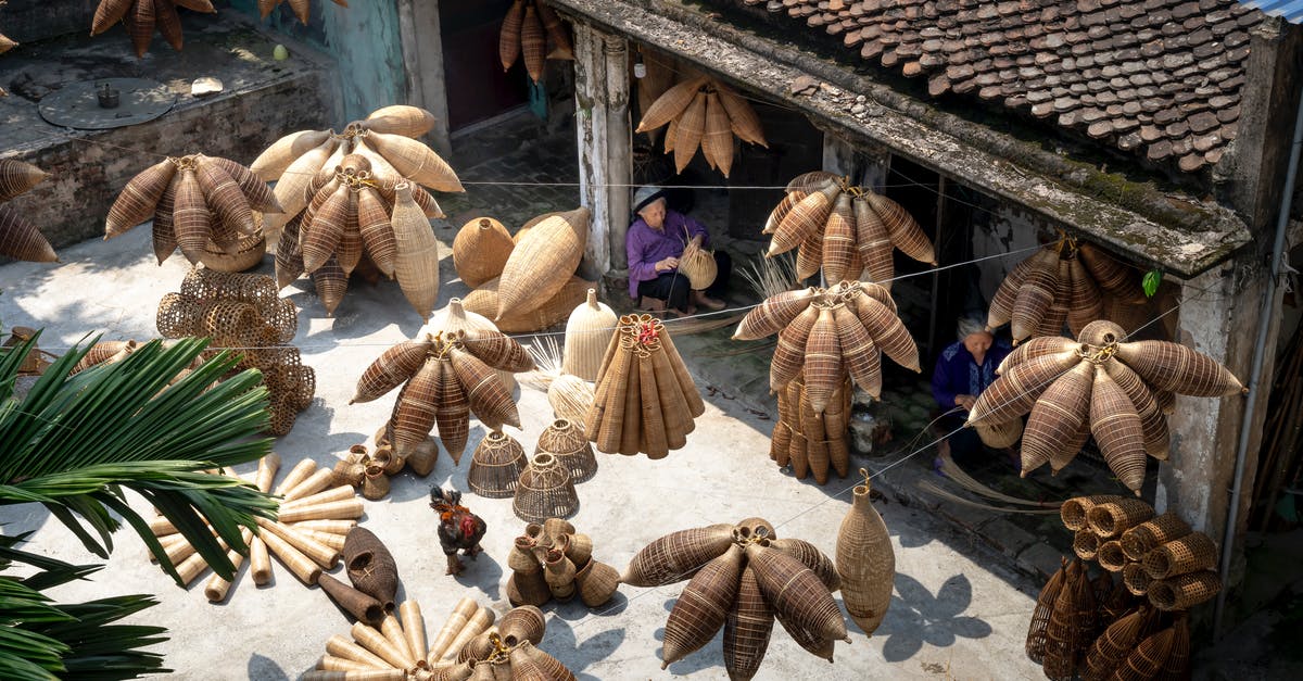 How does buying goods from outside prison work? - From above of people sitting and making bamboo fish traps while working on local bazaar in Vietnam in daylight