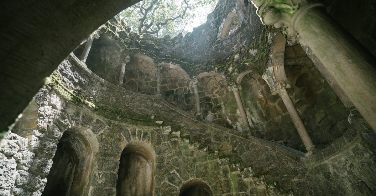 How does Chigurh know where to go to find Moss when the transponder isn't beeping initially? - From below of dark moss grown Initiation Well with spiral staircase at Regaleira estate in Portugal