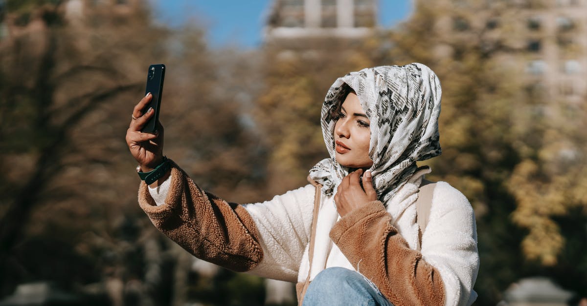 How does Dr. Perrow know Grace is Traveler 0027? - Gorgeous young Muslim female millennial in trendy outfit and hijab resting in autumn park and taking selfie on smartphone