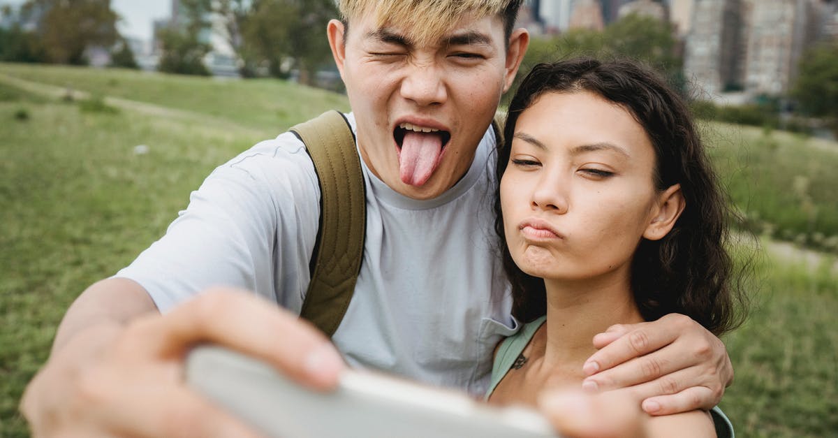 How does he have those memories? - Crop diverse couple grimacing while taking selfie on smartphone