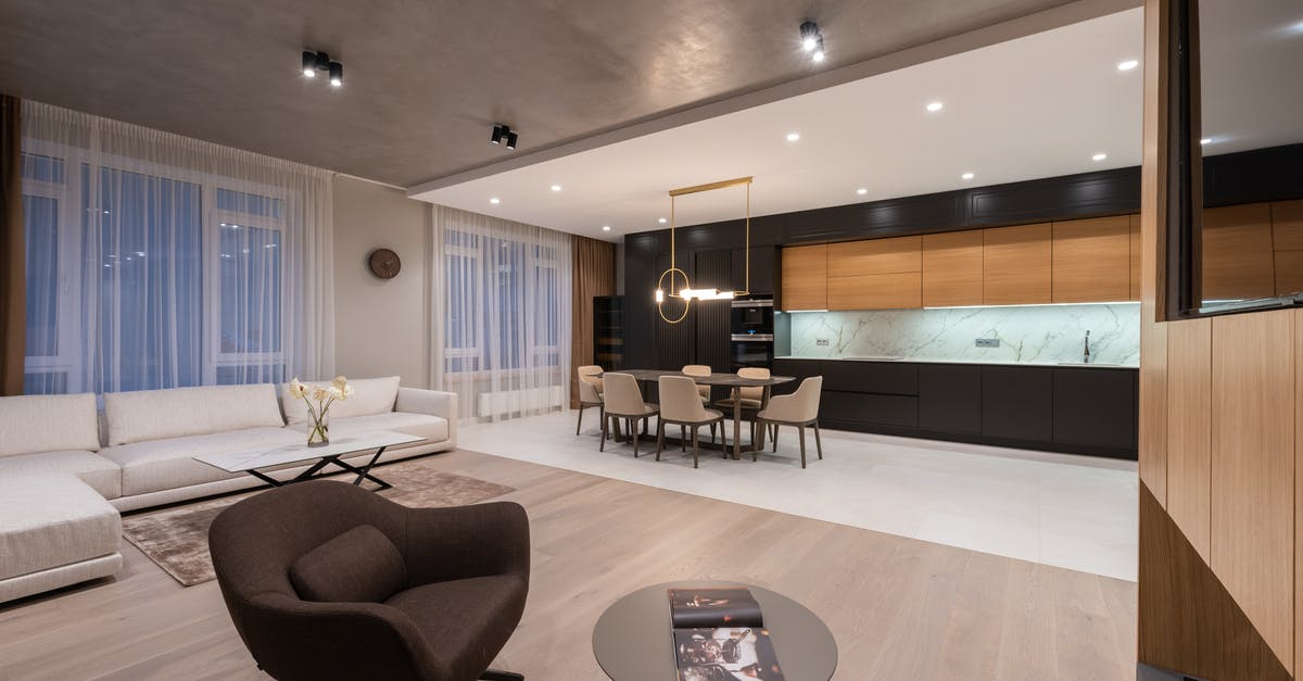 How does Light Yagami manage to hide a portable TV inside the chips packet? - Modern studio interior with armchair near couch and tables with chairs under lamps next to open kitchen and TV on wall