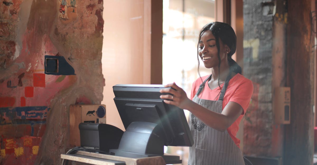 How does movie music staff know all the less known songs? - Cheerful American African waitress in apron working on counter monitor while registering order at cozy cafe