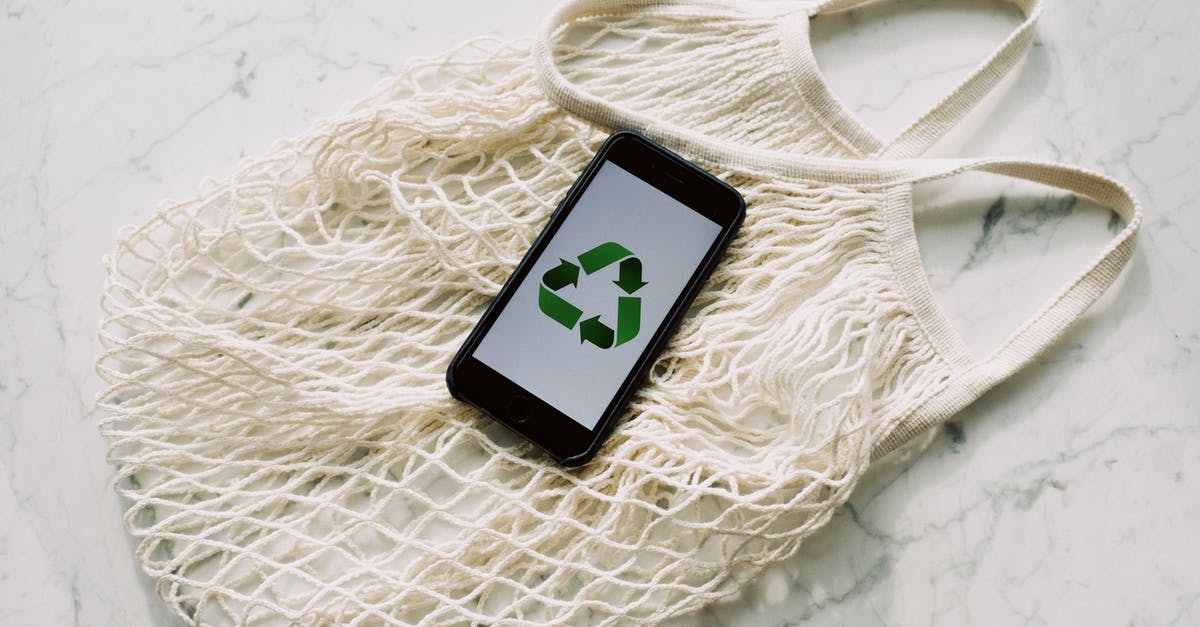 How does she apparently save him? - Overhead of smartphone with simple recycling sign on screen placed on white eco friendly mesh bag on marble table in room