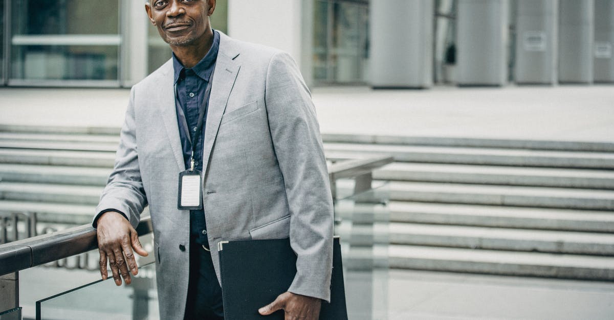 How does the first assistant camera focus if the director is pointing the camera? - Positive black businessman leaning on railing near modern business center
