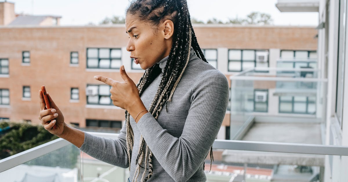 How does the mad scientist obtain a digital copy of the classified document? - Side view of young furious African American woman with braids in casual outfit pointing at smartphone screen while arguing during video call standing on balcony