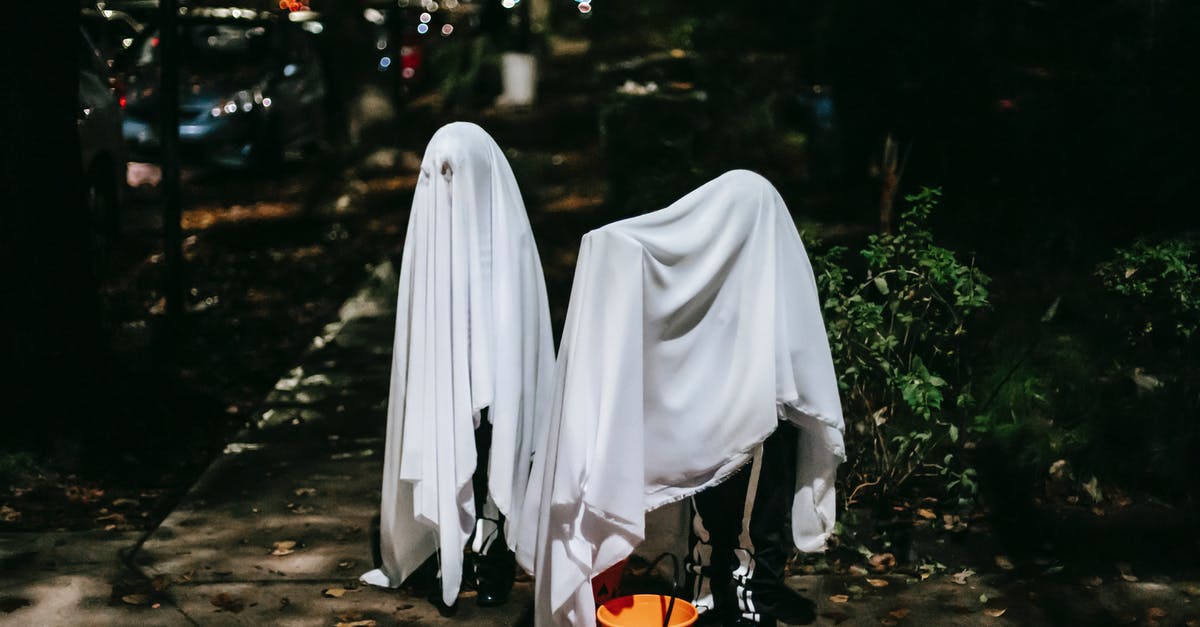 How does this apparition happen? - Unrecognizable children in ghost costumes with trick or treat bucket on urban pavement in twilight