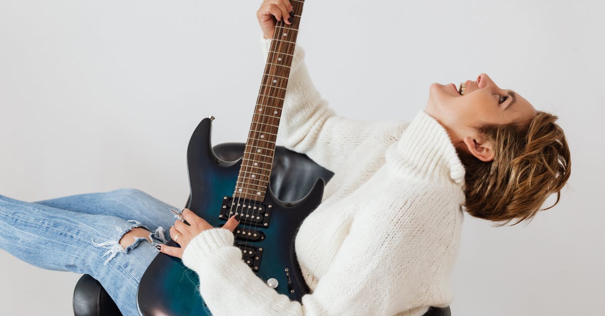 How does William know what song to play? - Side view of cheerful short haired female in casual clothes laughing while playing electric guitar in comfortable armchair against white background