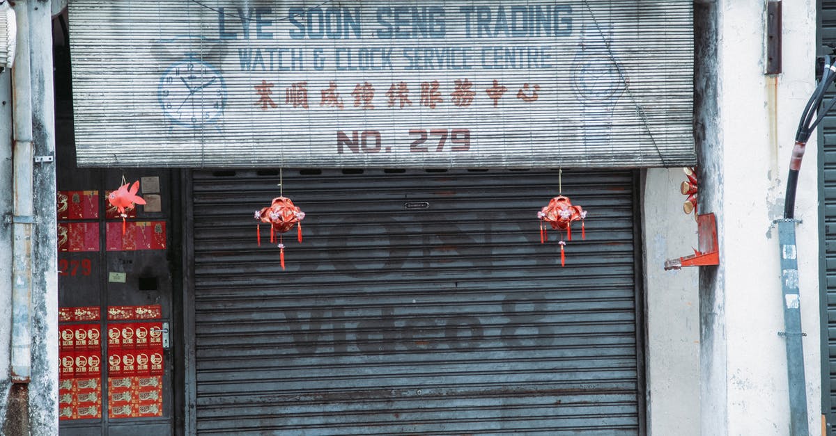 How exactly are subtitles and closed captions written for movies? - Exterior of closed aged service with signboard and traditional hanging decorations and black rolling gates located on street in city