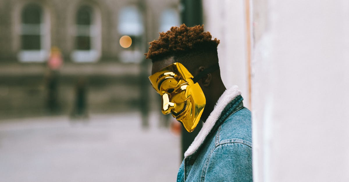 How is AFC Richmond playing against Man City again if they were relegated? - Side view of thoughtful African American activist wearing golden Anonymous mask as symbol of protest against current state policy standing near building on city street in daytime