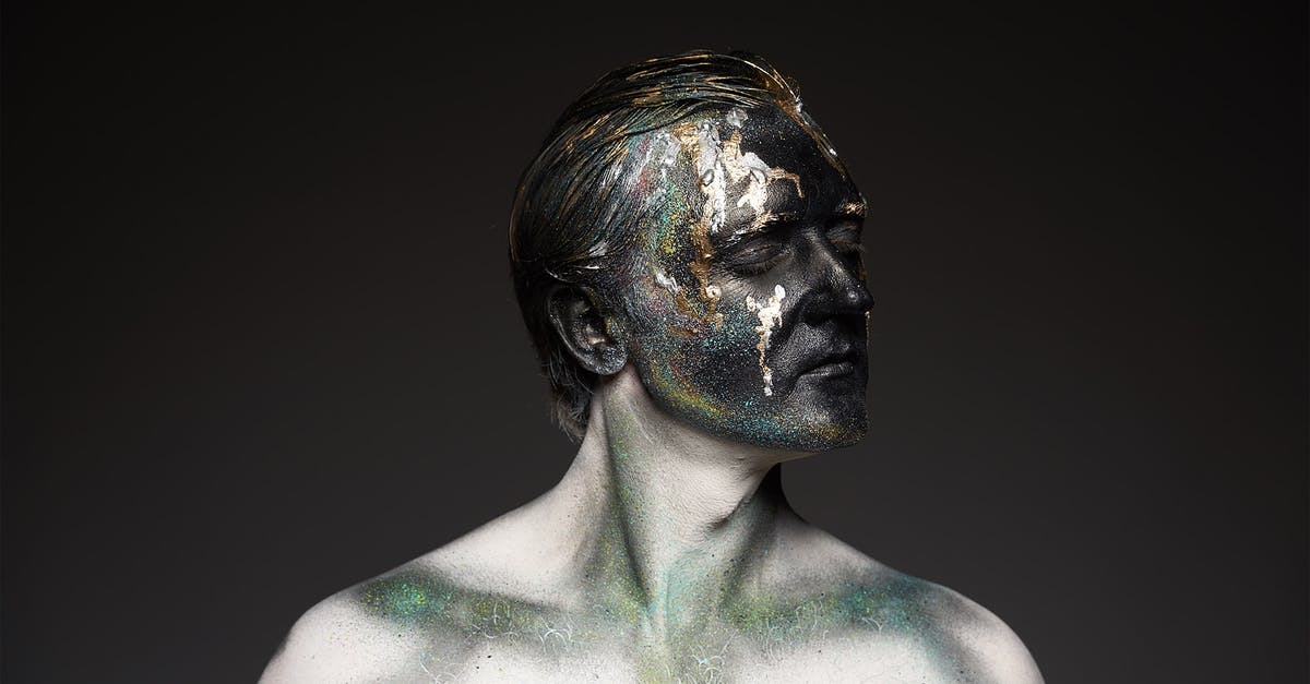 How is the "solid black eyes" effect done? - Male shirtless model with glowing glitters on black painted face covering eyes standing on black backdrop