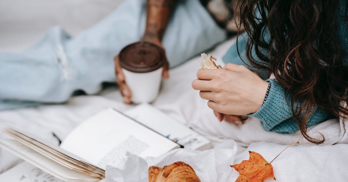 How is the relationship between the reader and the story affected by movies that are released prior to the completion of a book series? - Unrecognizable multiracial couple with takeaway hot drink and croissant lying on white plaid with opened book during picnic in autumn day