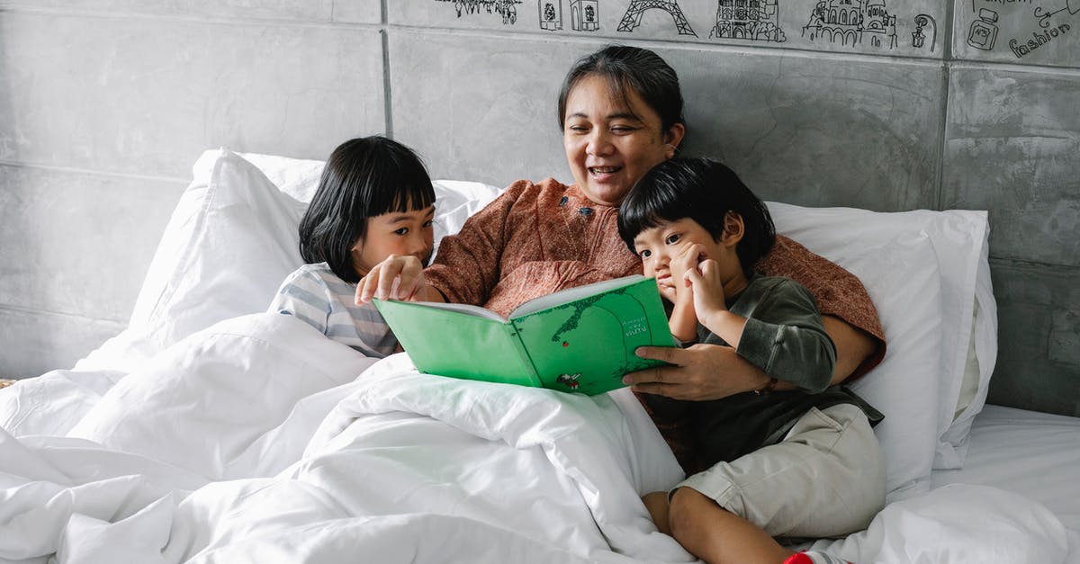 How is the relationship between the reader and the story affected by movies that are released prior to the completion of a book series? - Adorable little Asian sibling lying on bed with smiling grandmother and reading book