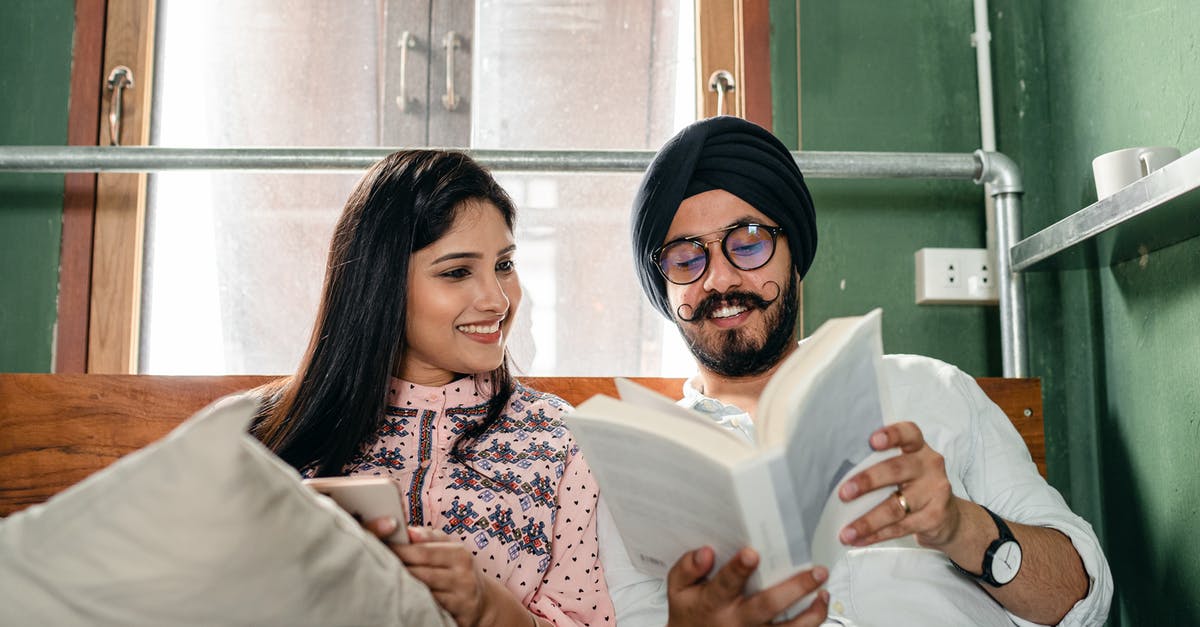 How is the relationship between the reader and the story affected by movies that are released prior to the completion of a book series? - Smiling couple with book on bed