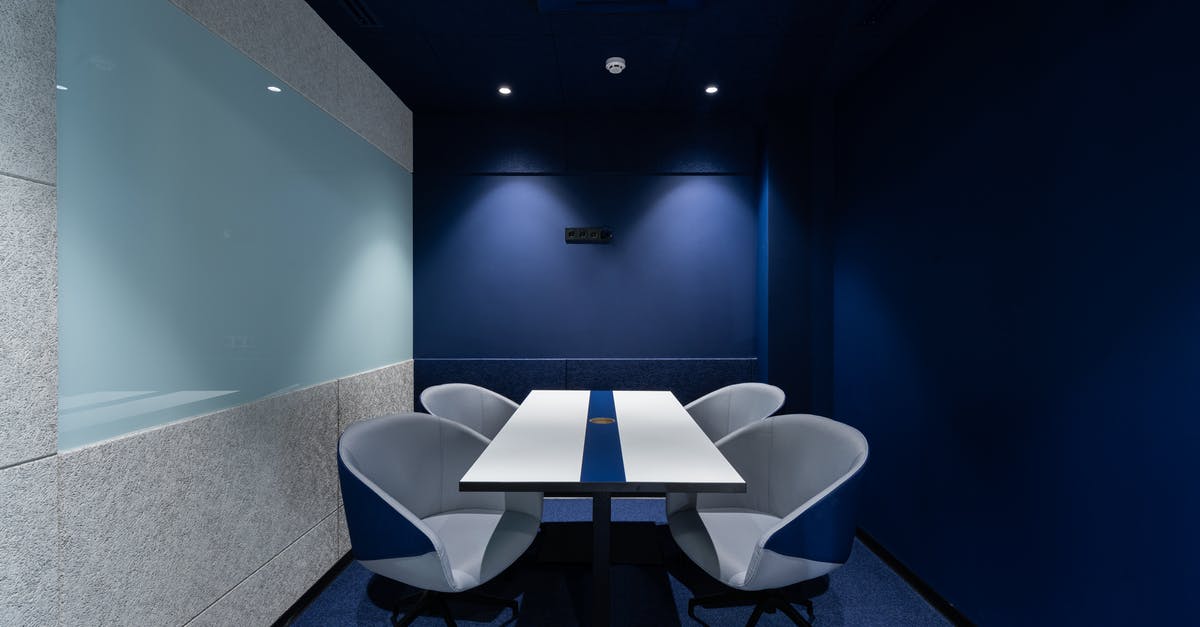 How long has Alice been fighting the Umbrella Corporation? - Comfortable chairs placed on carpet at long white desk in modern conference room with blue walls in contemporary business center