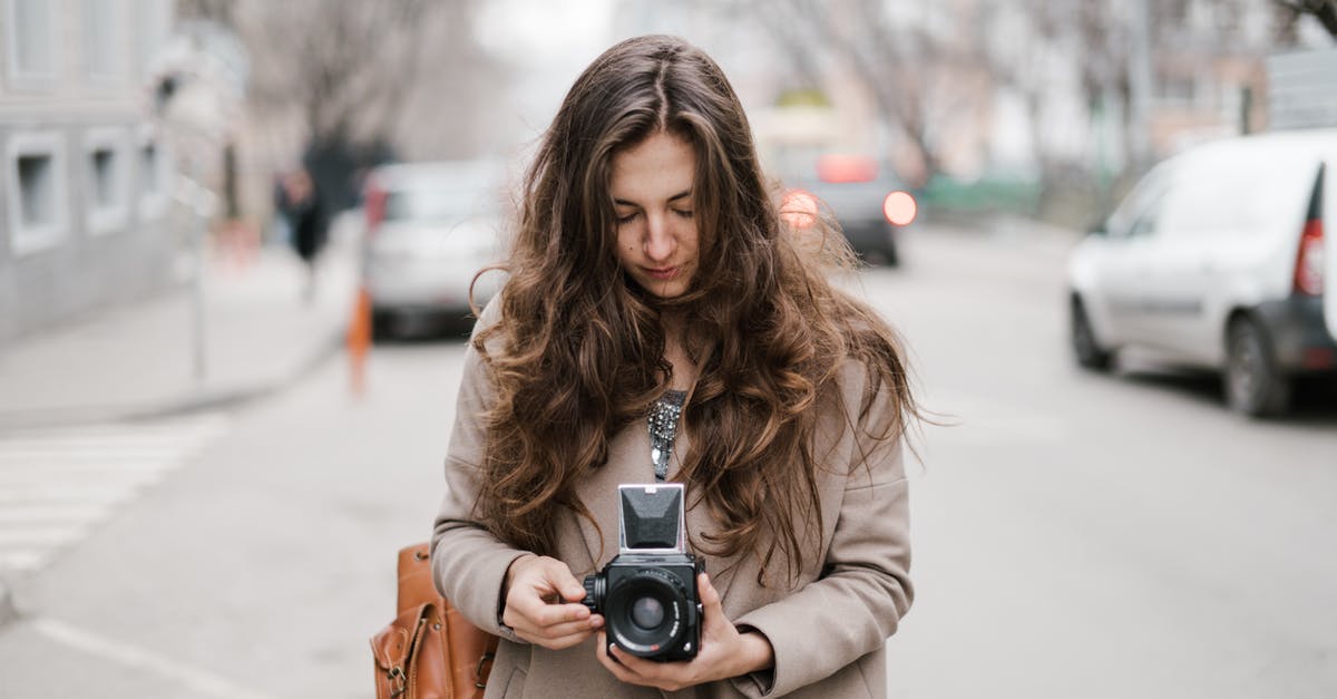 How long must a Hollywood film wait to use the same title of an older film? - Young pensive female with long hair in casual outfit walking on street and setting up retro camera