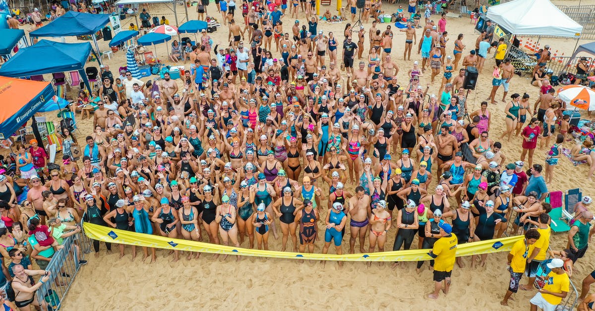 How many people are there onboard the train in Snowpiercer (2013)? - Drone view of crowded beach with people dressed in swimsuits standing behind tape ready for swim competition