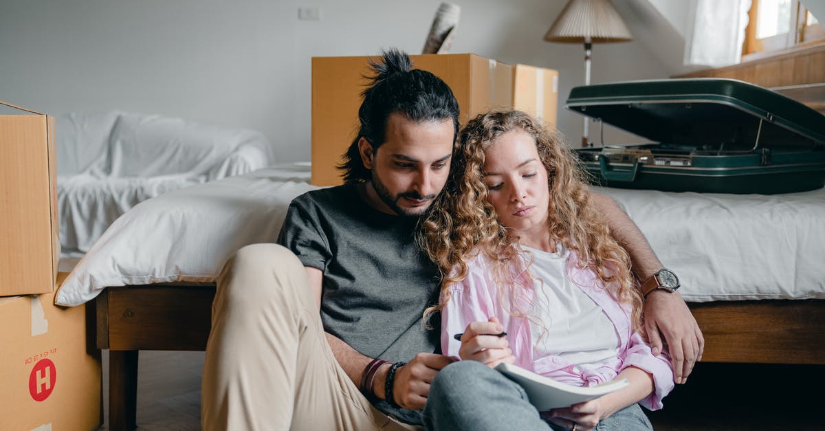 How much of what the second couple said was planned, and how much was improvised? - Thoughtful male and female in casual wear sitting near bed among boxes together and taking notes while moving house