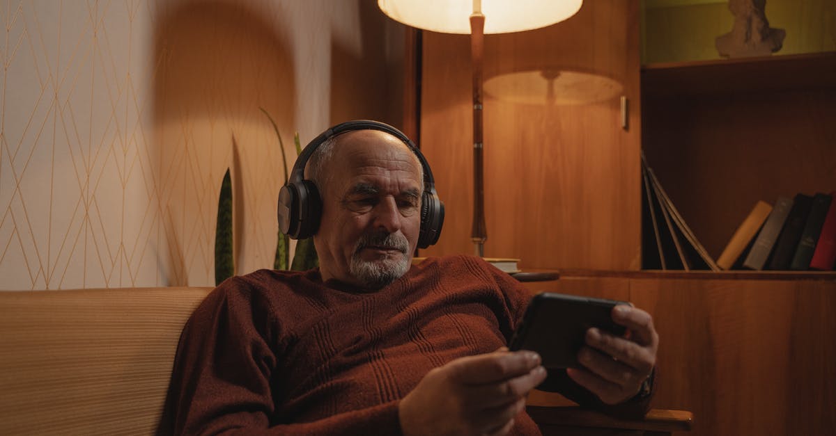 How old is Adam in The Goldbergs? How does this reconcile with watching Star Wars? - Photograph of an Elderly Man with Headphones Holding His Phone