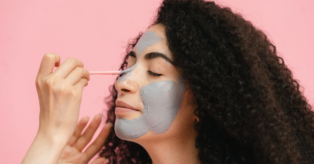 How was a retinal scan possible when the subject had closed eyes? - Womans hand painting her friends nose with gray clay mask