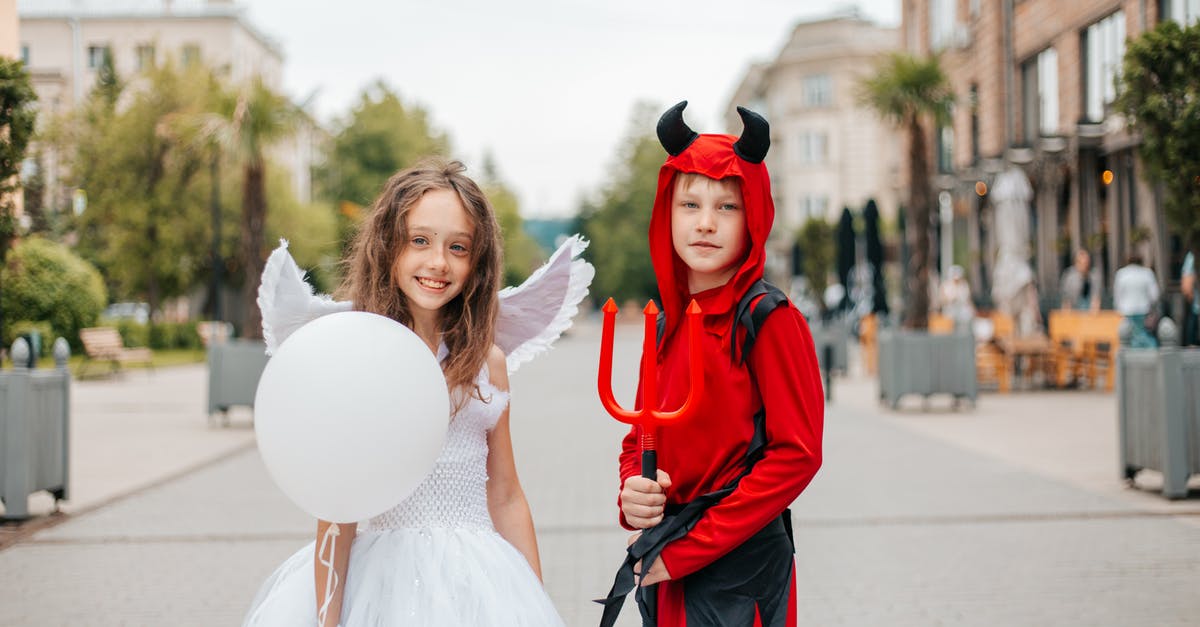 How was Devil able to hit Sister Charlotte in Annabelle: Creation? - Delighted girl and boy in angel and devil costumes standing together in street on blurred background and looking at camera