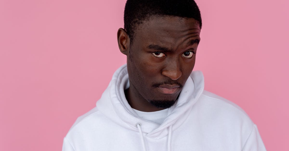 How was Suspicion (1941) supposed to end? - Serious African American male model wearing white sweatshirt looking at camera with unsure gaze against pink background