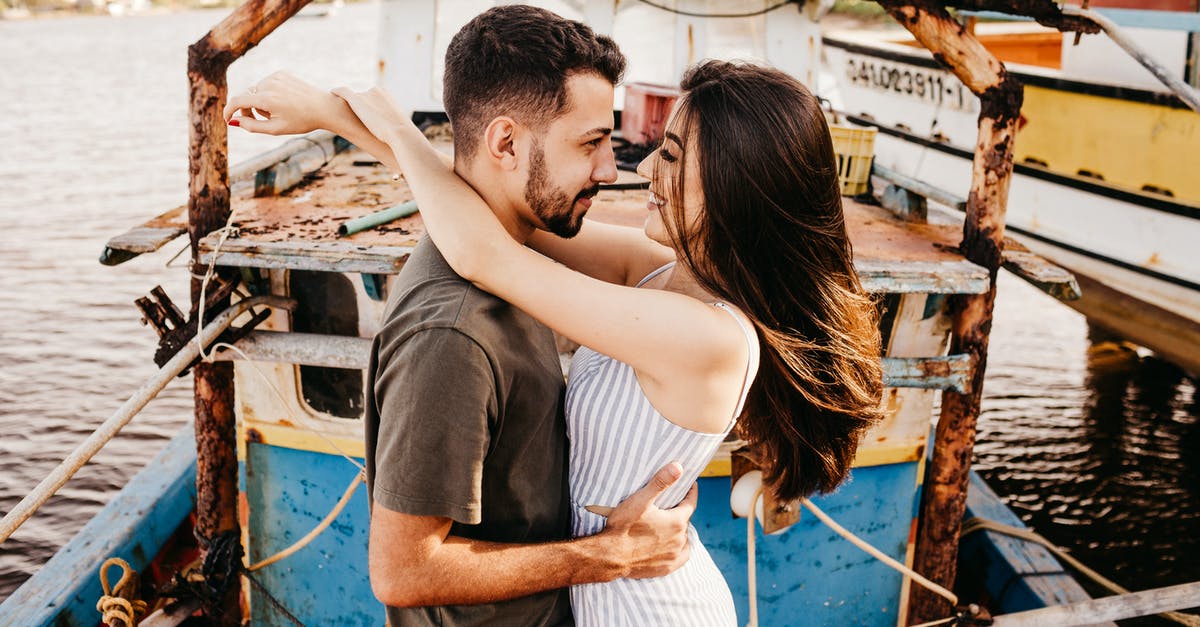 ID a scene where a woman shoots a man on a boat without flinching [closed] - Side view cheerful young couple in stylish summer wear bonding and looking at each other with love while standing on old boat floating on river