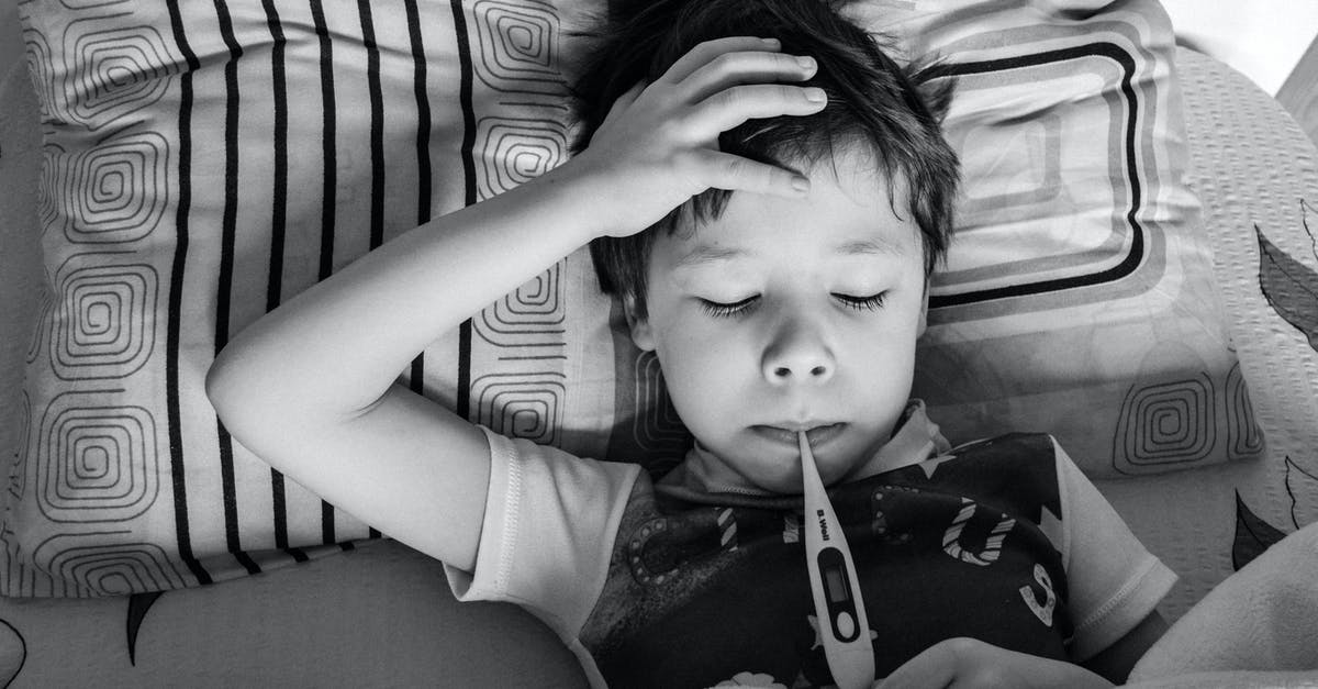 In Doctor Sleep what makes the True Knots so dangerous? - Black and white overhead view of child in casual clothing measuring body temperature with electronic thermometer while lying on bed under blanket