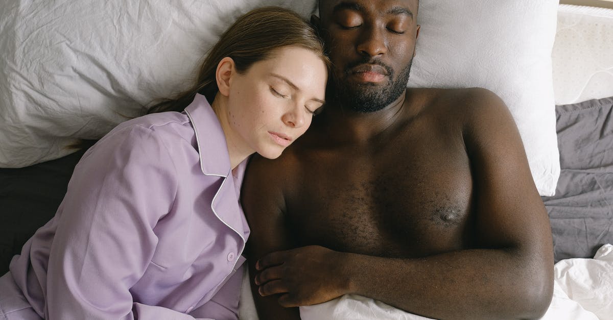 In "A View To A Kill" why does Zorin let Bond sleep with May Day? - Top view of woman in nightwear and African American man sleeping together on comfortable bed in light bedroom at home