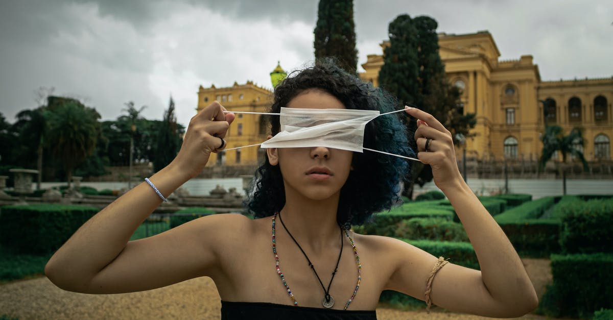 In the Doctor Who episode Hide how does the Alien become trapped? - Serious young ethnic female with curly hair in light top covering eyes with medical mask while standing in city park against cloudy sky