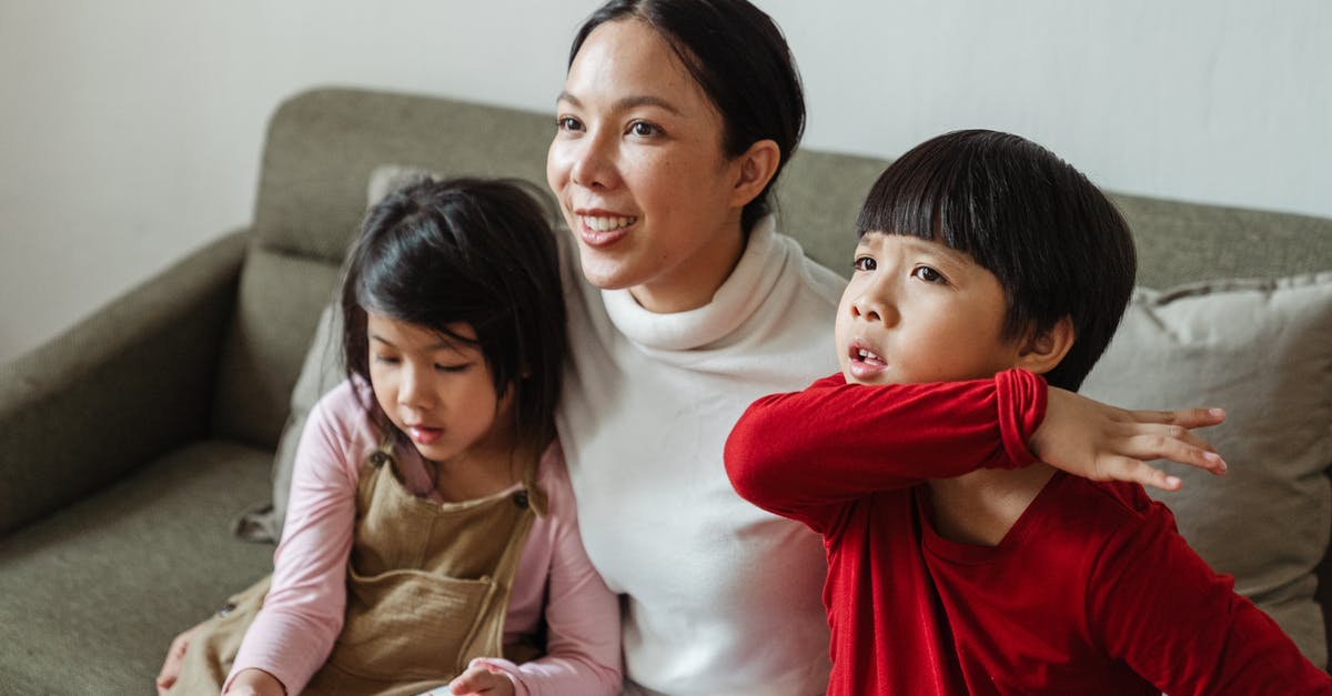In the movie Little Fish are there any moments like these? - Positive Asian mom and little children watching interesting cartoon on TV while spending day together on comfortable couch