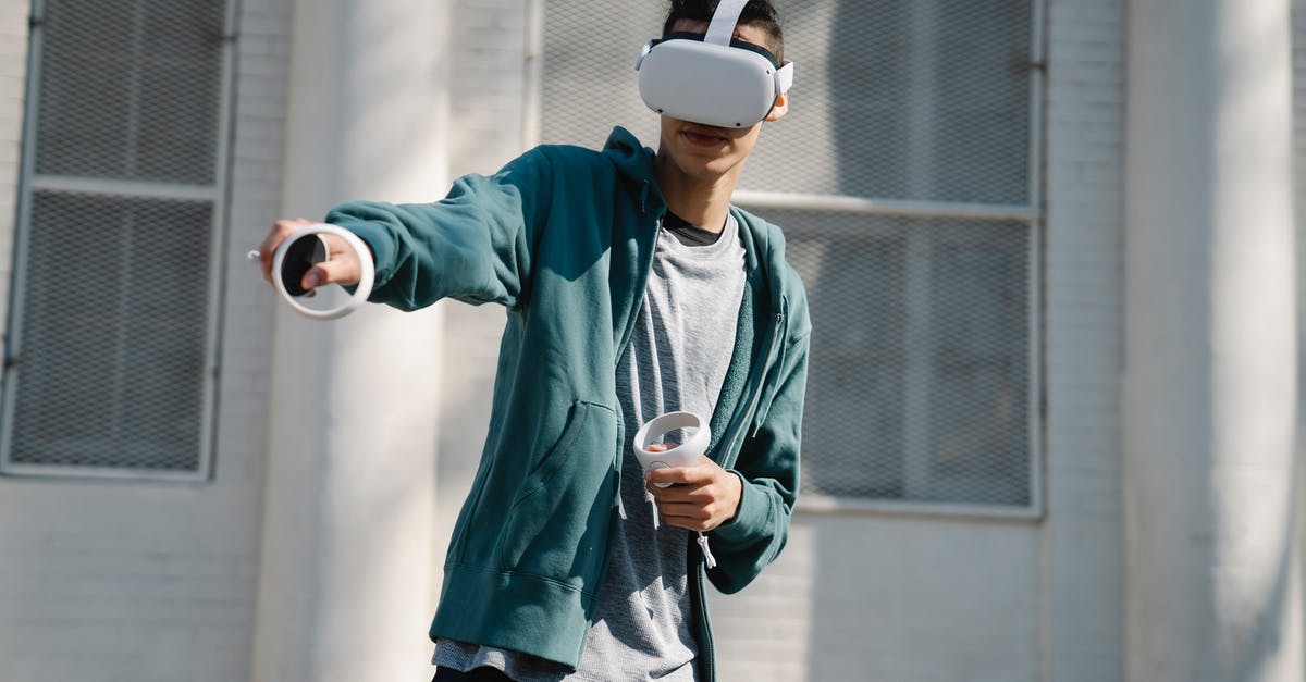 In which District is the Hunger Games conducted? - Man in virtual reality goggles with controllers playing video game against urban building in sunlight
