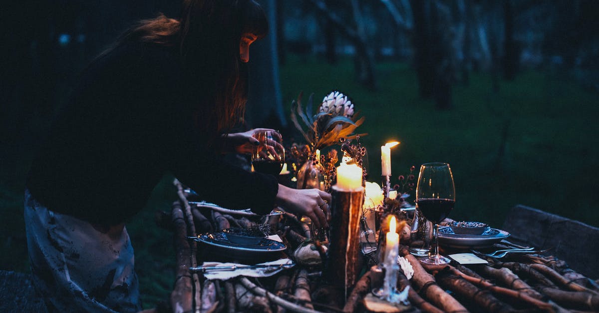 In which military branch did Ted Striker serve? - Side view of unrecognizable lady serving wineglasses on table with plates and forks with knifes near candles in evening in nature near forest