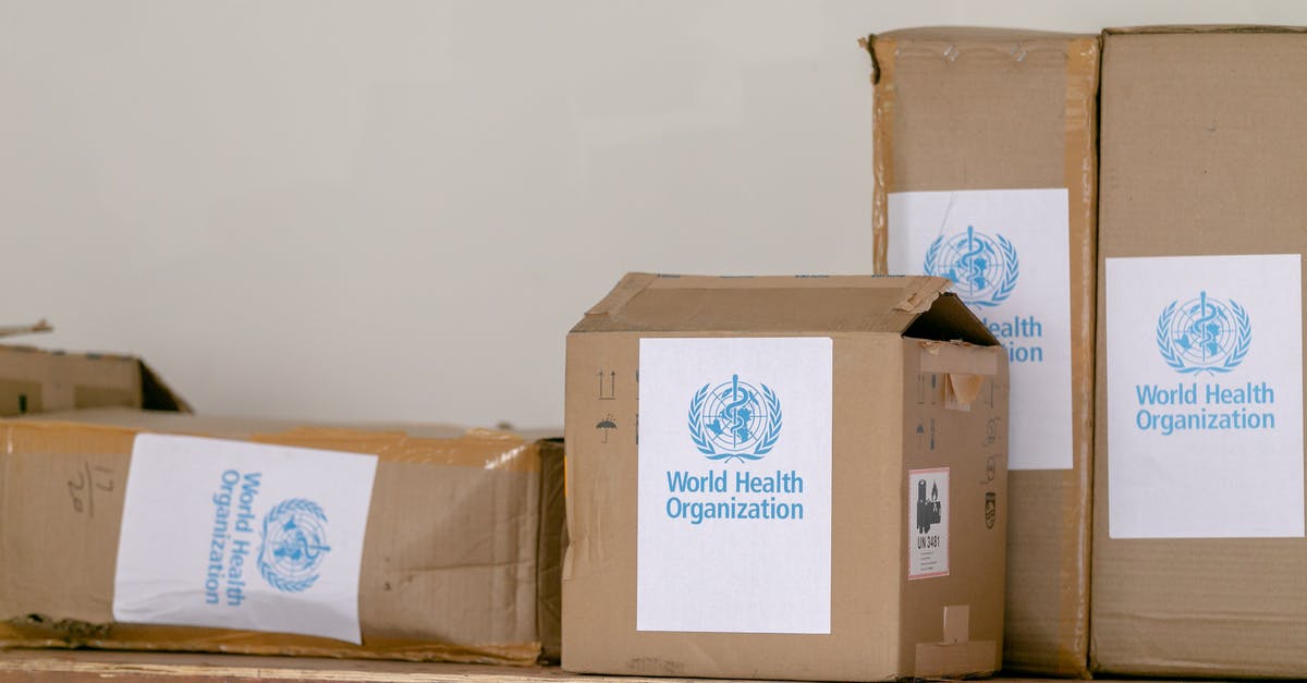 Initial scene at the World Health Organization - Blue emblem sticker of World Health Organization on carton boxes heaped on table