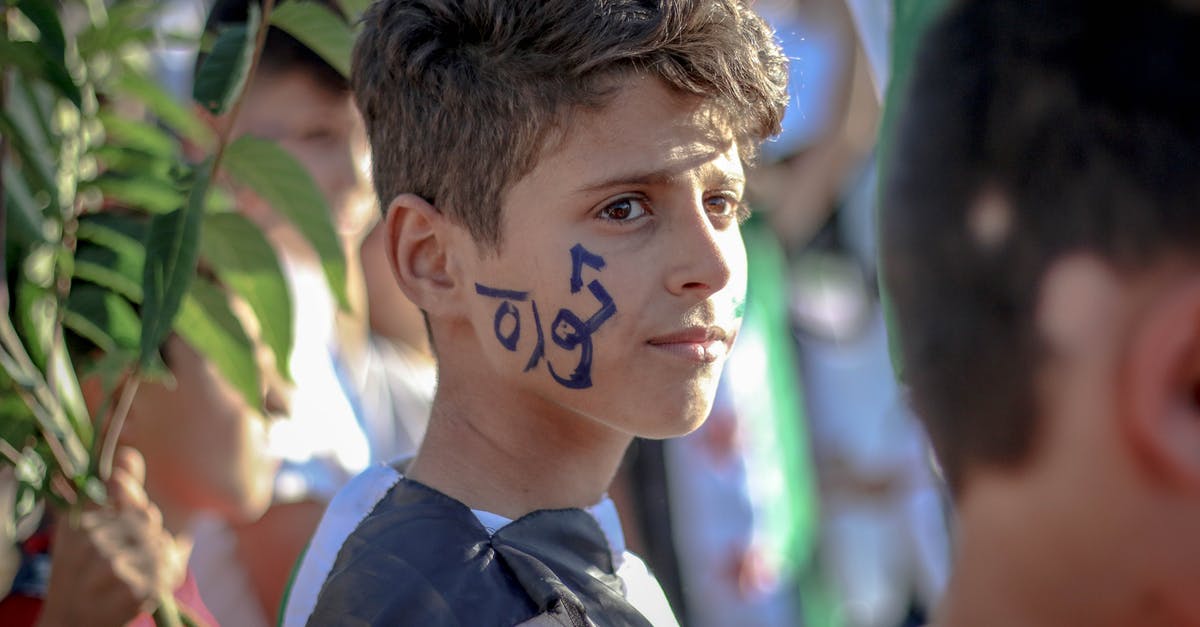 Is Beast Boy's transformation of Justice League vs. Teen Titans a nod to Genomorphs from Young Justice? - Side view of ethnic teenage boy with Arabic inscription on face standing on crowded street at protest movement against state policy
