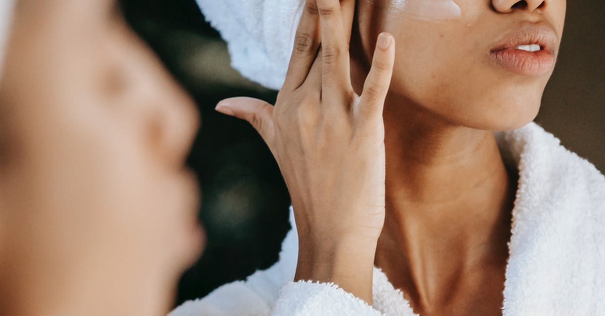 Is every appearance of a product in a movie sponsored? - Crop unrecognizable young ethnic female in terry robe applying moisturizing cream on cheek while reflecting in mirror