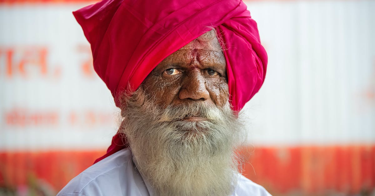 Is God really a Red Sox fan? - Elderly ethnic bearded male in bright national red turban looking at camera on blurred background