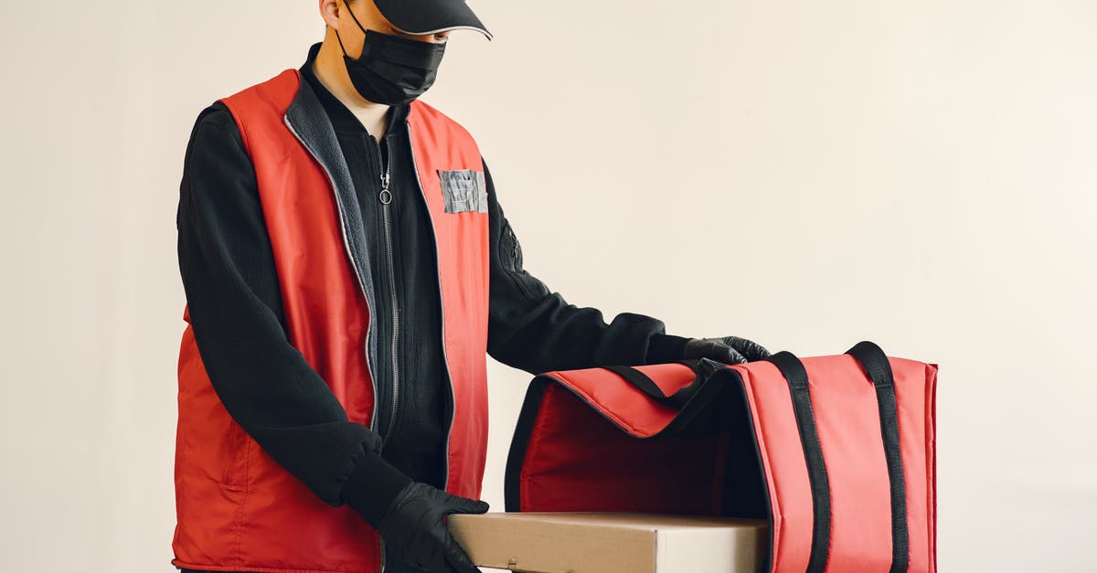 Is it really possible to put a virus in a machine you don't know? [duplicate] - Young delivery man wearing surgical facial mask and gloves for preventing disease during coronavirus pandemic putting pizza box in thermo bag for safety food delivery