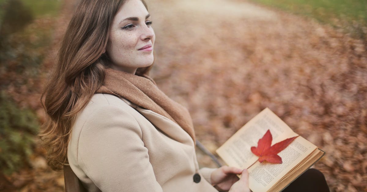 Is Jack and Rose's love story real? - Side view of peaceful young female in warm coat and scarf sitting on bench with open book in hands and looking away pensively while resting in autumn park