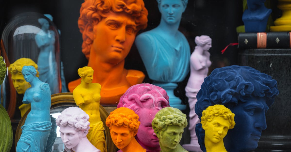 Is Lucifer a David Bowie Fan? - Multicolored head sculptures of David near bright statuettes placed in store with abundance of souvenirs and black pillar with book