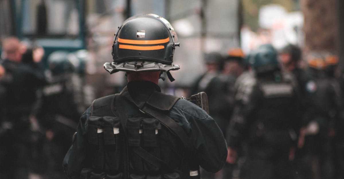 Is Rorschach bulletproof? - Back view of anonymous policeman in helmet and bulletproof vest maintaining law and order while standing on city street