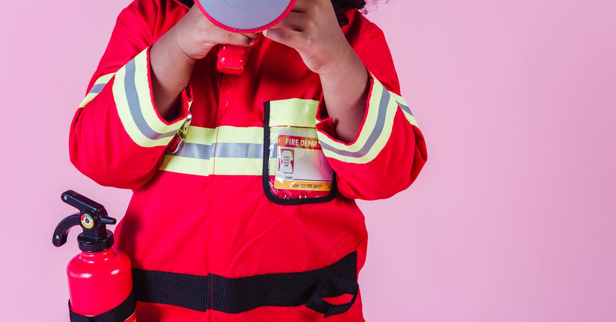 Is the kid a reference to another Marvel hero? - Crop unrecognizable little ethnic kid wearing fireman costume and fire extinguisher while using loudspeaker toy and standing on pink background
