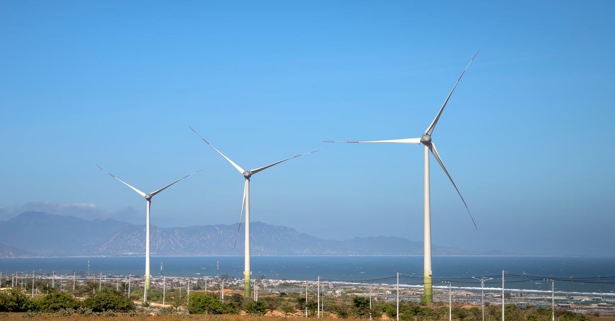 Is the Land of Ooo really a post apocalyptic Earth? - Rows of wind generators on land with plants against sea and mountain in daylight