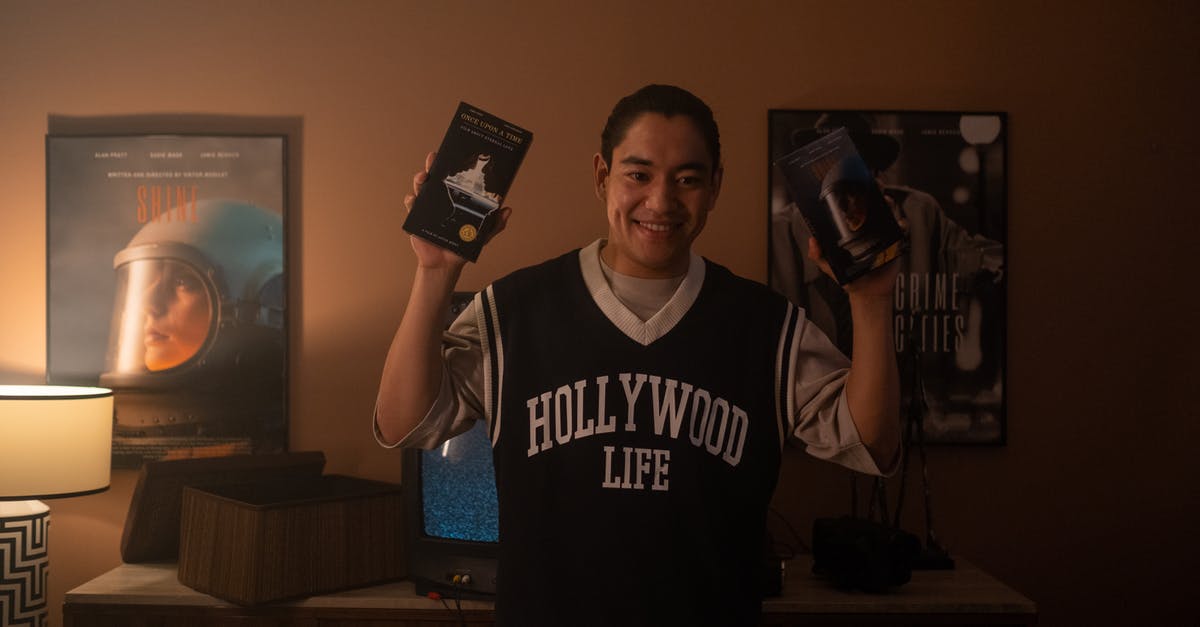 Is the movie showing true events, or Lorraine's lies? - Man holding 2 different films on vhs videotapes.